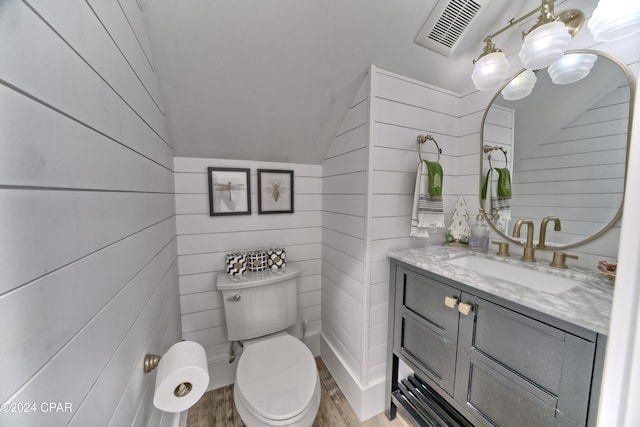 bathroom with wooden walls, hardwood / wood-style floors, lofted ceiling, and toilet