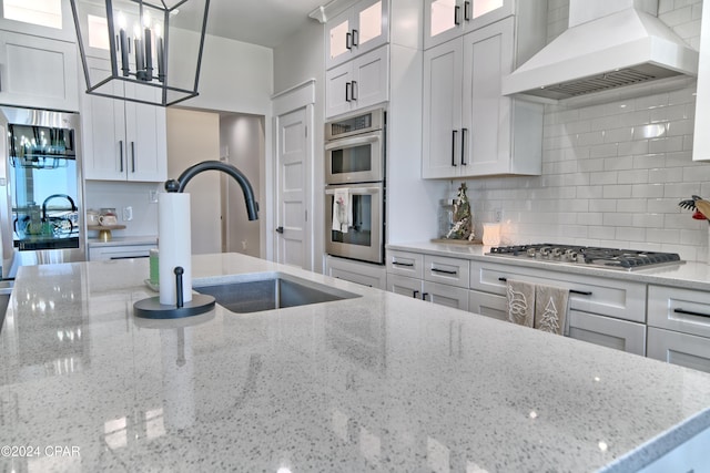 kitchen featuring appliances with stainless steel finishes, white cabinets, decorative light fixtures, and custom exhaust hood