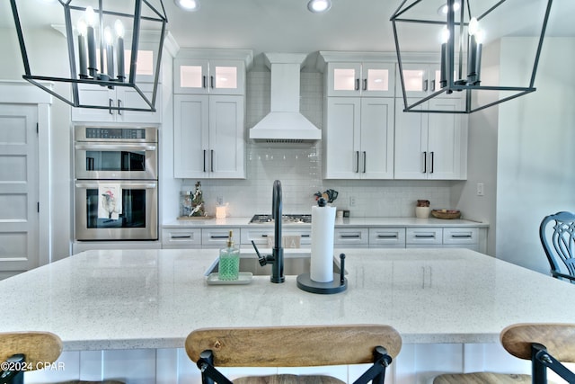 kitchen featuring hanging light fixtures, white cabinets, stainless steel double oven, and custom exhaust hood