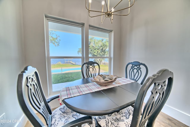 dining area with a water view, wood-type flooring, and a notable chandelier