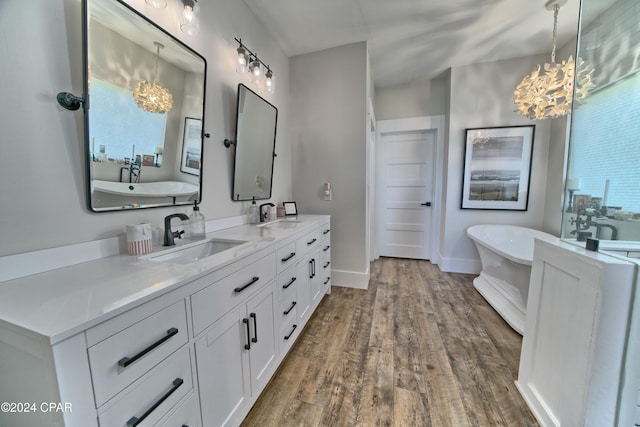 bathroom featuring a notable chandelier, wood-type flooring, a bath, and a wealth of natural light