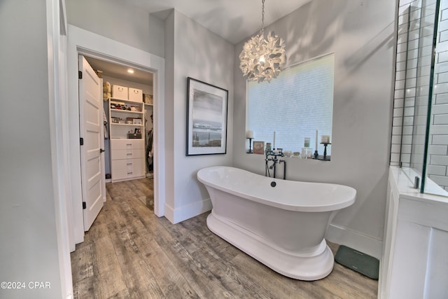 bathroom with hardwood / wood-style floors, a tub, and a chandelier