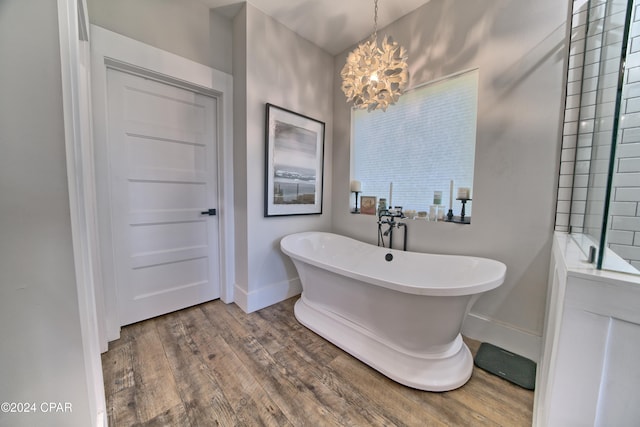 bathroom with hardwood / wood-style floors, a washtub, and a chandelier