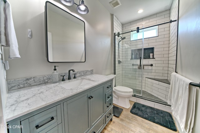 bathroom featuring vanity, toilet, an enclosed shower, and wood-type flooring