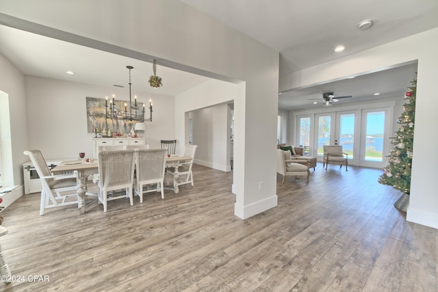 dining space featuring ceiling fan with notable chandelier and light wood-type flooring