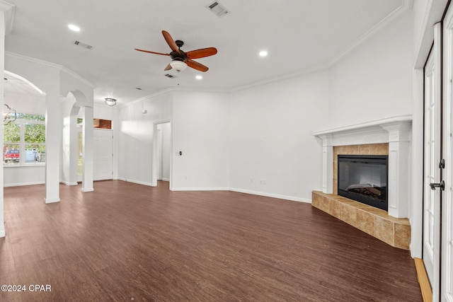 unfurnished living room featuring a tile fireplace, dark wood-type flooring, ceiling fan, and ornamental molding