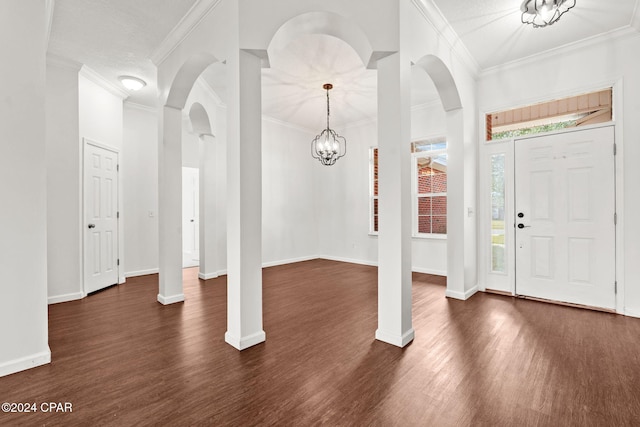 entryway with dark hardwood / wood-style flooring, ornamental molding, and an inviting chandelier