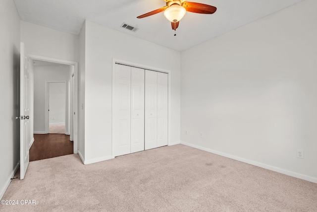 unfurnished bedroom with ceiling fan, light carpet, and a closet