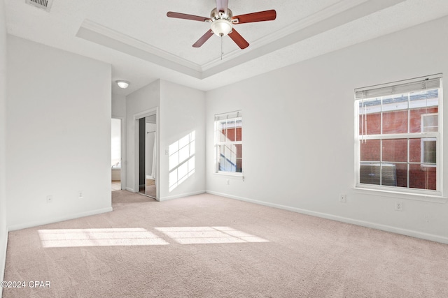 carpeted spare room featuring a raised ceiling, ceiling fan, and ornamental molding