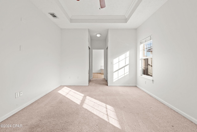 unfurnished room featuring light colored carpet, a raised ceiling, ceiling fan, and ornamental molding