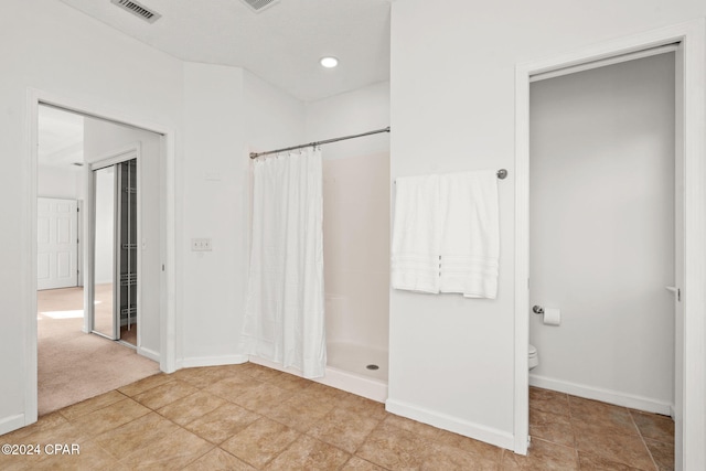 bathroom featuring toilet, tile patterned flooring, and walk in shower