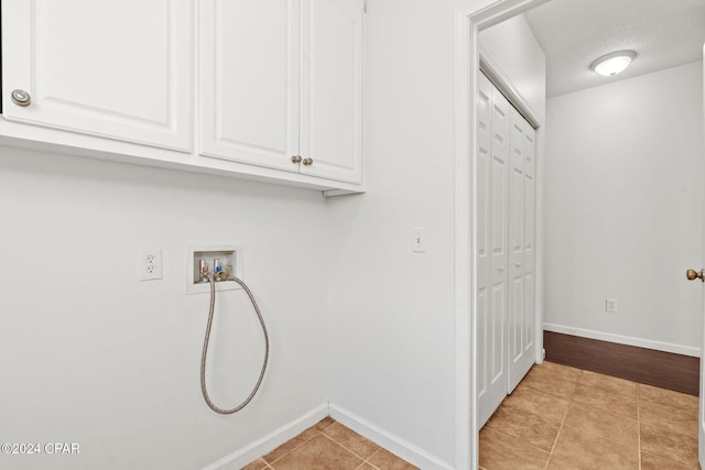 laundry area with cabinets, washer hookup, a textured ceiling, and light tile patterned flooring