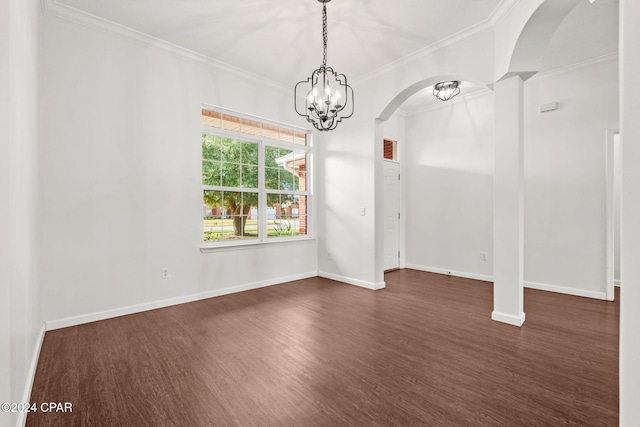 spare room featuring crown molding, dark wood-type flooring, and an inviting chandelier