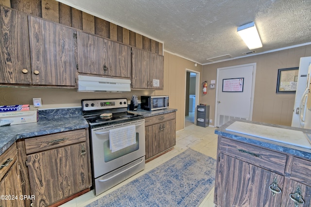 kitchen featuring light tile patterned floors, stainless steel appliances, a textured ceiling, and ornamental molding