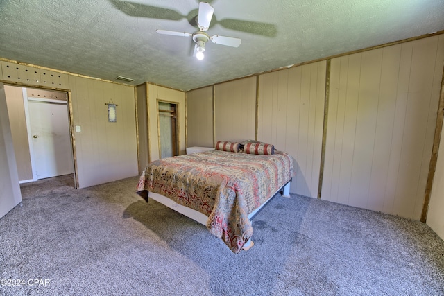 carpeted bedroom with a textured ceiling, ceiling fan, and wood walls