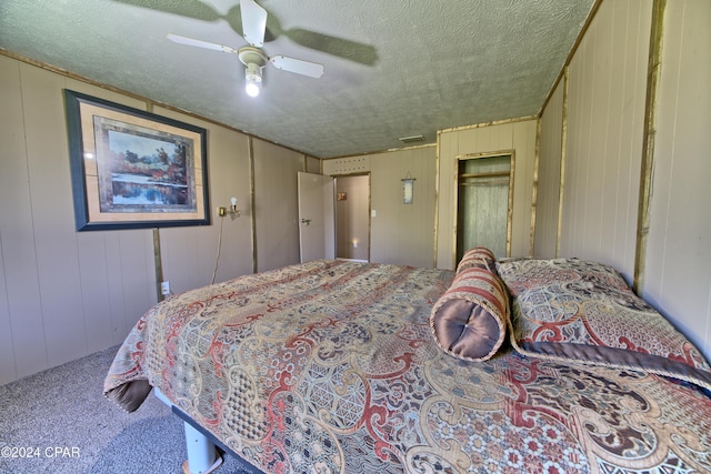 carpeted bedroom featuring a textured ceiling, ceiling fan, and wood walls