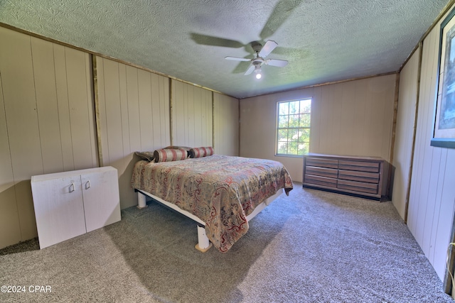 carpeted bedroom featuring ceiling fan, wood walls, and a textured ceiling