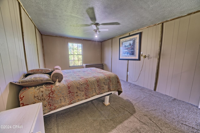 carpeted bedroom with a textured ceiling, ceiling fan, and wood walls