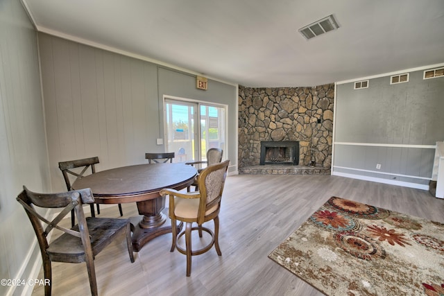 dining space with a fireplace, light hardwood / wood-style floors, and ornamental molding