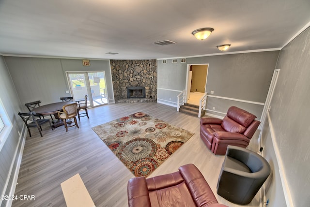 living room with hardwood / wood-style floors, a stone fireplace, and ornamental molding