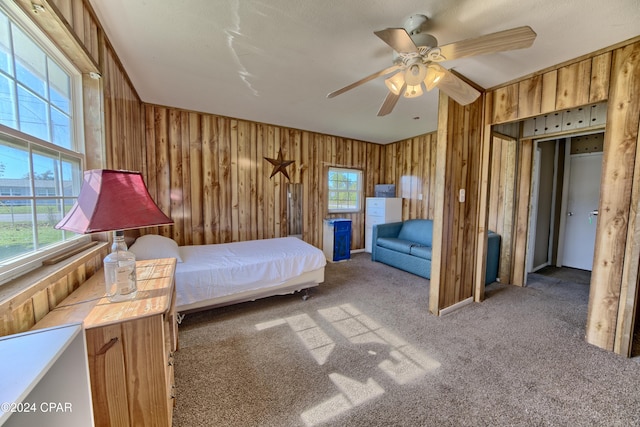 unfurnished bedroom with carpet, ceiling fan, and wooden walls