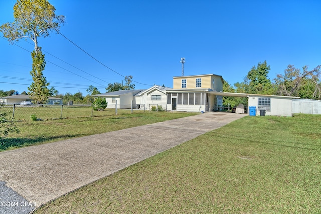 view of front of home featuring a carport, a sunroom, and a front lawn