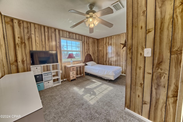 bedroom with carpet flooring, ceiling fan, and wood walls