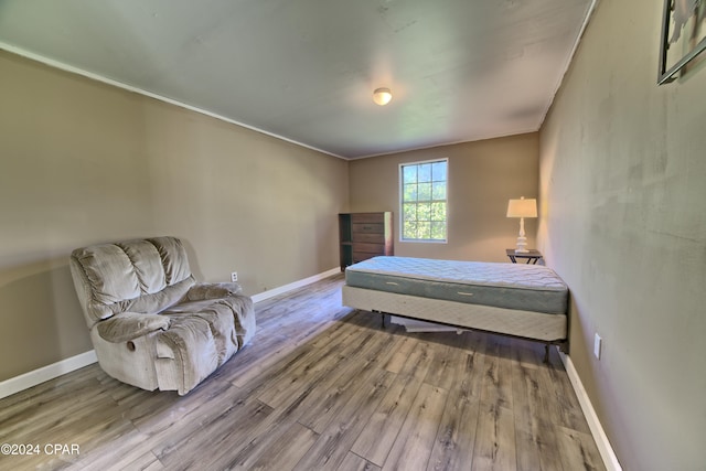 bedroom with light hardwood / wood-style floors and ornamental molding