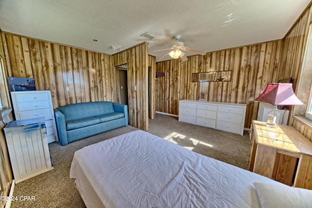 carpeted bedroom with ceiling fan and wooden walls