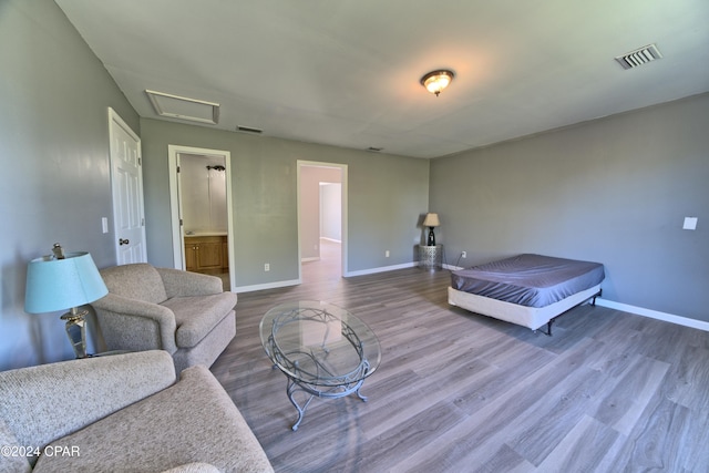 bedroom with ensuite bath and hardwood / wood-style flooring