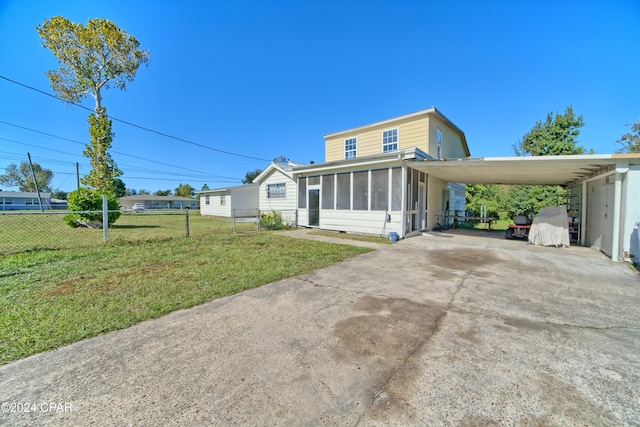 view of front of home with a front lawn, a carport, and a sunroom