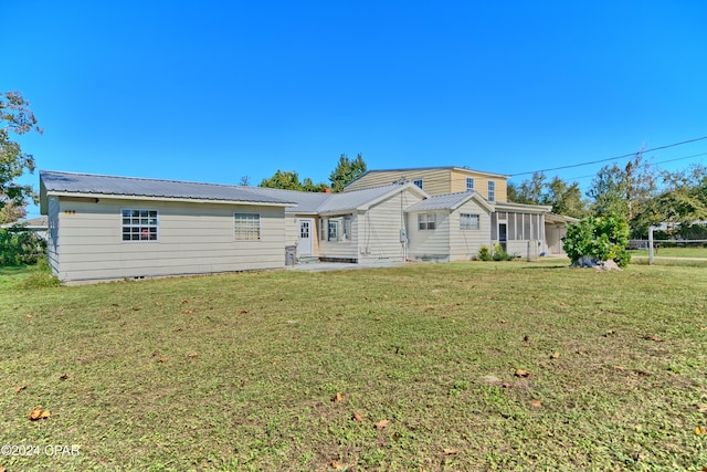 back of house with a lawn and a sunroom