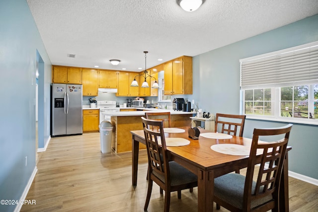 dining area with a textured ceiling and light hardwood / wood-style flooring