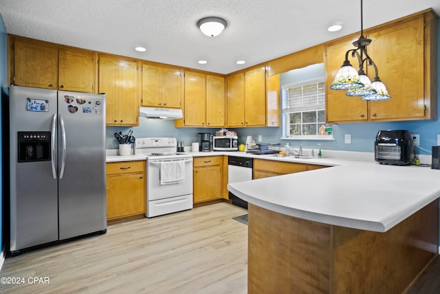 kitchen featuring sink, kitchen peninsula, pendant lighting, appliances with stainless steel finishes, and light wood-type flooring