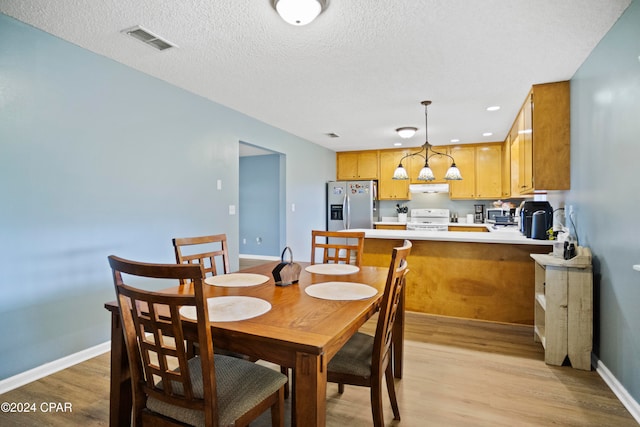 dining room featuring a textured ceiling and light wood-type flooring