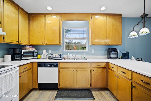 kitchen featuring white appliances, exhaust hood, sink, hanging light fixtures, and light hardwood / wood-style floors