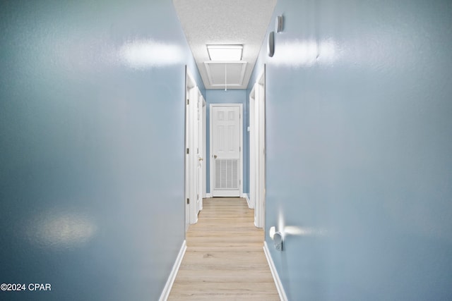 hall featuring light hardwood / wood-style floors and a textured ceiling