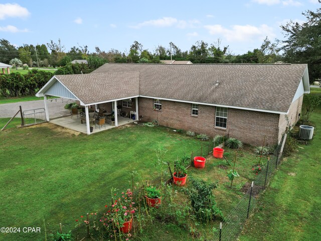 rear view of property with a lawn, a patio area, and central AC