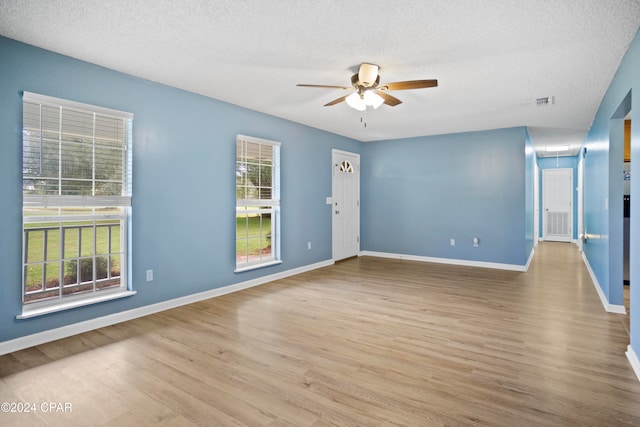 empty room with ceiling fan, a textured ceiling, and light hardwood / wood-style flooring