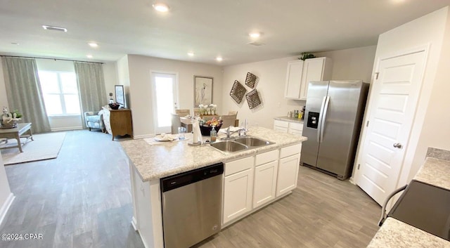 kitchen with sink, appliances with stainless steel finishes, a kitchen island with sink, white cabinets, and light wood-type flooring