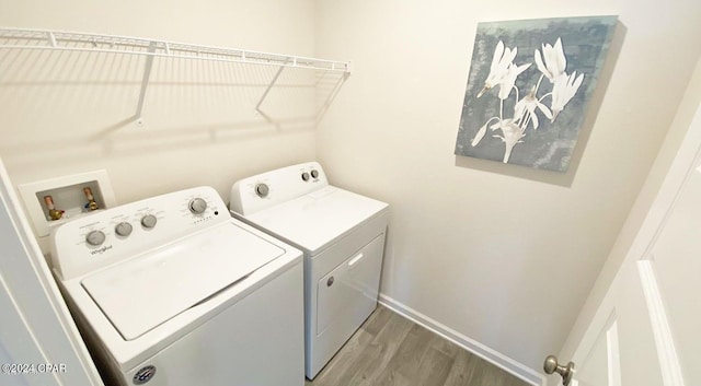 clothes washing area with hardwood / wood-style flooring and washer and clothes dryer