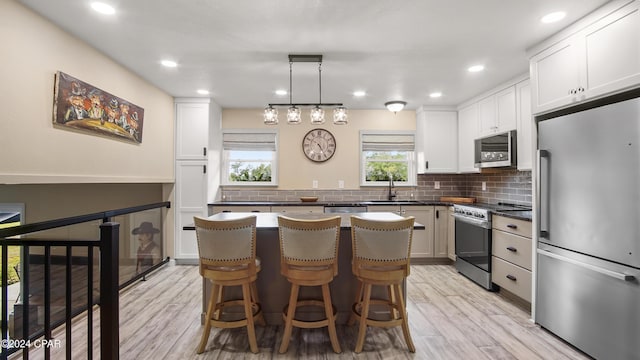 kitchen with light wood-type flooring, white cabinetry, and stainless steel appliances