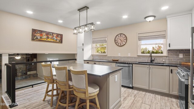 kitchen with backsplash, white cabinets, stainless steel appliances, and light hardwood / wood-style floors