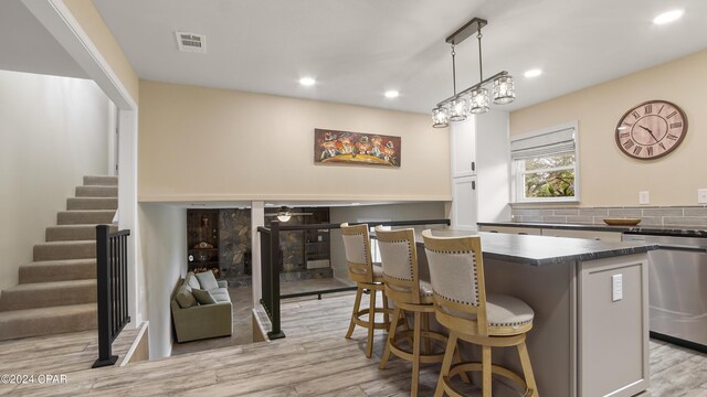 kitchen with sink, a center island, light hardwood / wood-style flooring, decorative light fixtures, and appliances with stainless steel finishes