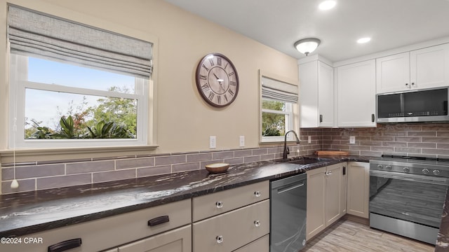 kitchen with decorative backsplash, appliances with stainless steel finishes, sink, dark stone countertops, and white cabinets