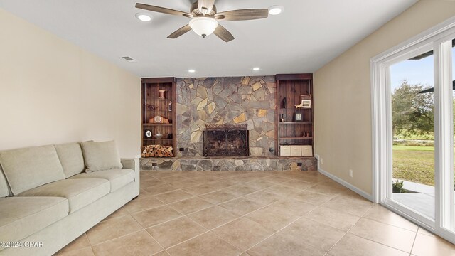 tiled living room with ceiling fan and a fireplace