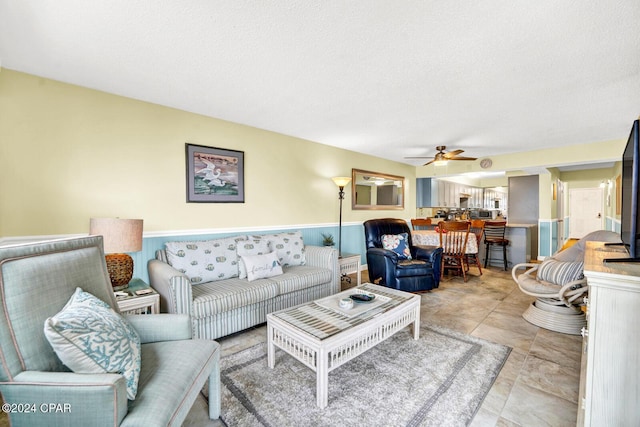 living room with a ceiling fan, tile patterned flooring, and a textured ceiling