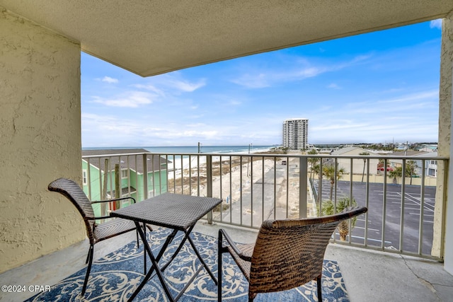 balcony with a water view and a view of the beach