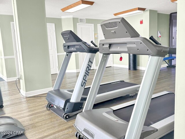 gym with ornamental molding, a textured ceiling, and hardwood / wood-style flooring