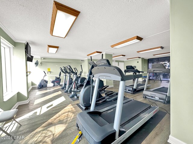 exercise room featuring crown molding, wood-type flooring, and a textured ceiling